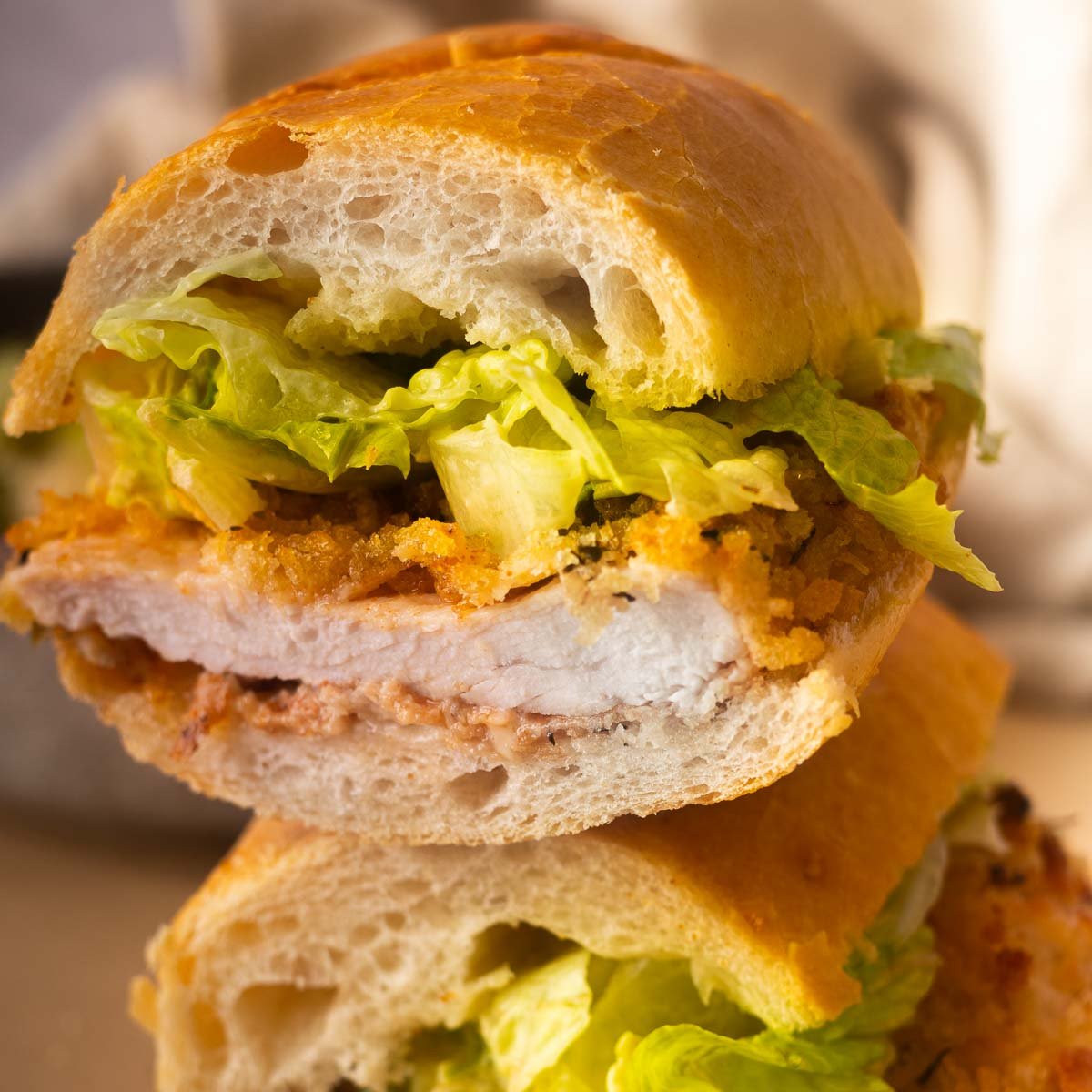 Baked chicken caesar sandwich with lettuce on a fresh baguette, close-up view.