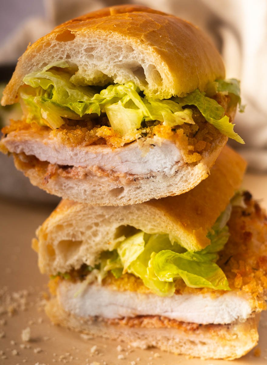 Baked chicken caesar sandwich with fresh lettuce on a crusty baguette, close-up view.