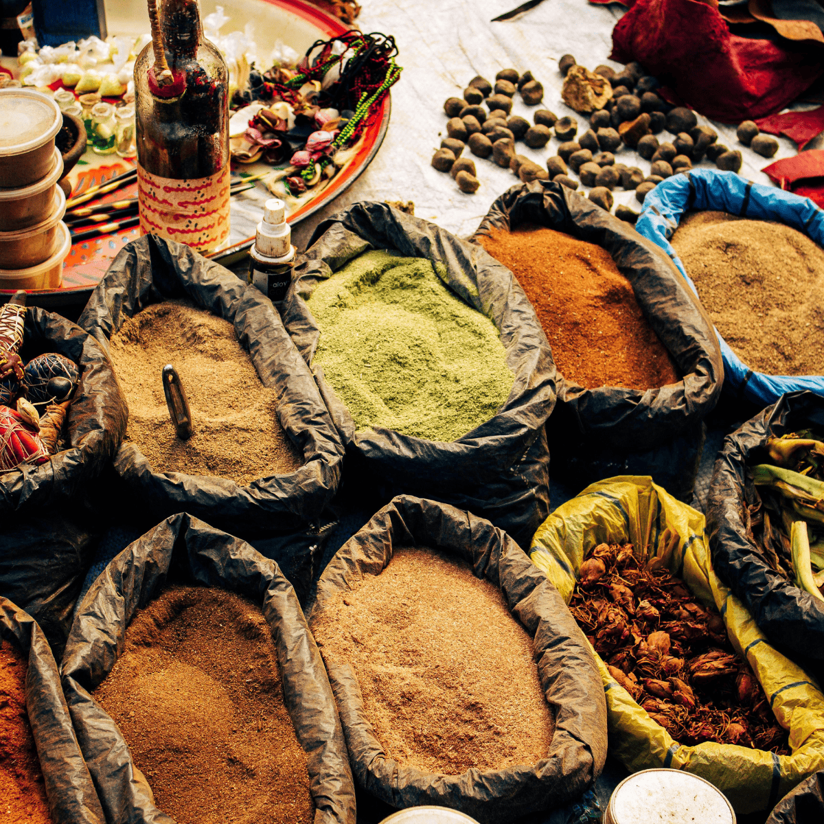 Mediterranean pantry staples including colorful spices in open bags at a market stall with various herbs and decorative items.
