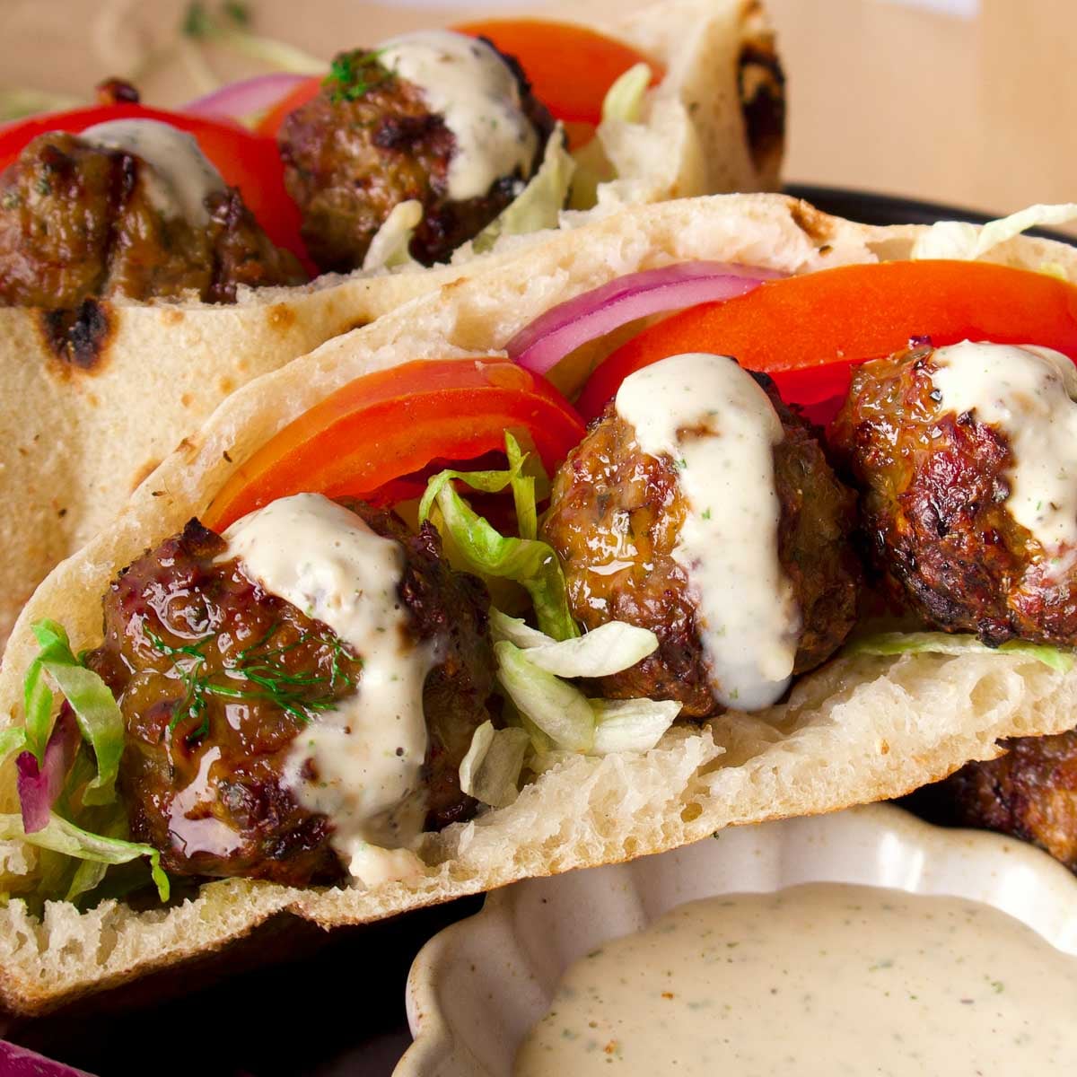 meatballs in a pita bread with sauce on it