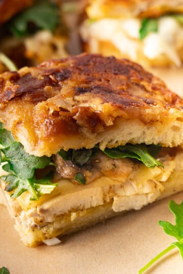 Caramelized Onion Focaccia Chicken Sandwich with chicken, arugula, melted cheese, and caramelized onions on toasted bread.