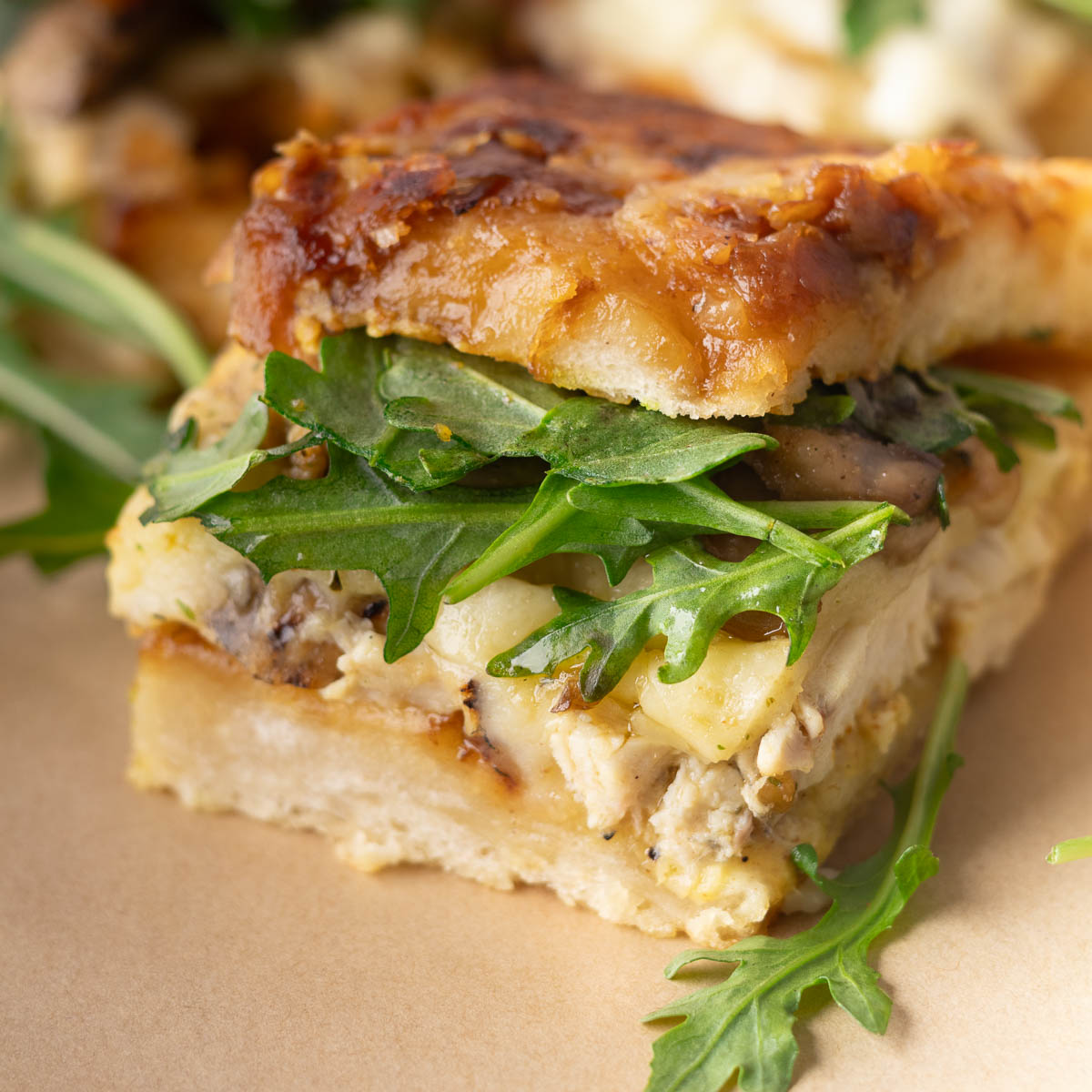 Caramelized Onion Focaccia Chicken Sandwich with arugula, melted cheese, and crispy toasted bread.