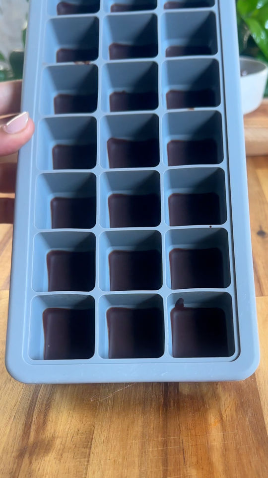 Silicone ice cube tray filled with chocolate.