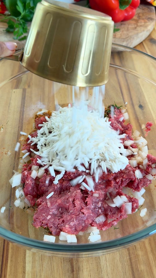 Pouring rice into a bowl with ground meat and chopped onions.