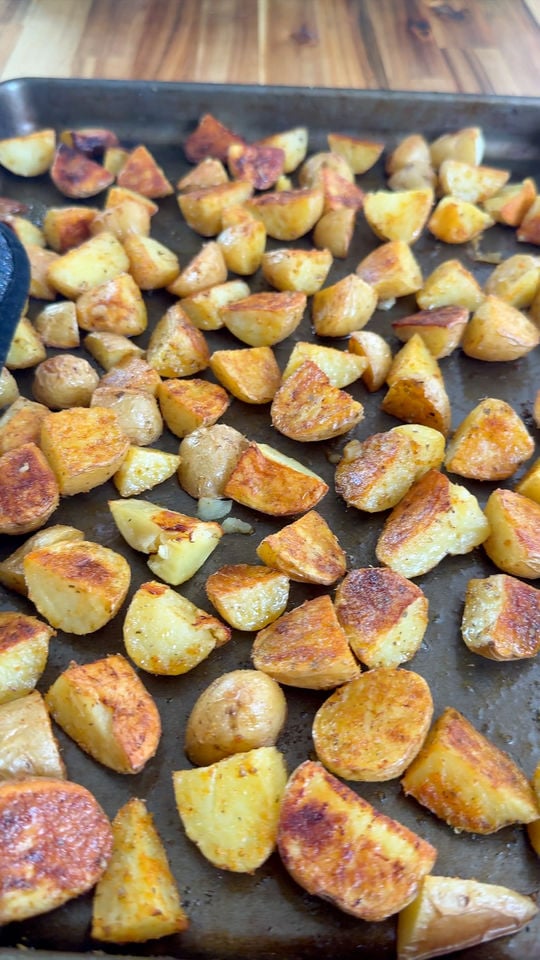 Roasted potato wedges with crispy golden edges on a baking sheet.