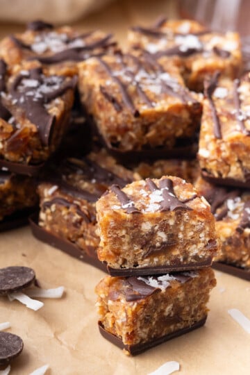Stack of samoas cookie bites with coconut flakes on brown paper.
