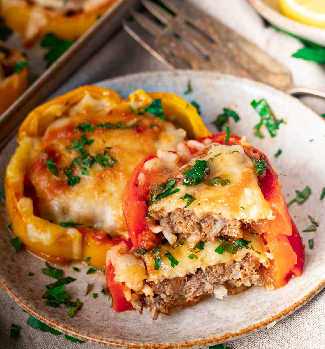 Stuffed bell peppers with melted cheese and parsley garnish on a ceramic plate.