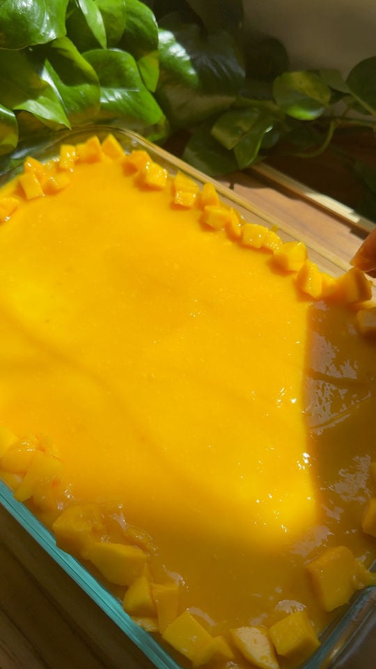 Glass dish with mango tiramisu topped with diced mango.