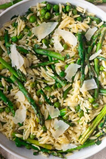Asparagus Orzo Pasta Salad with asparagus, peas, and parmesan in a white bowl.