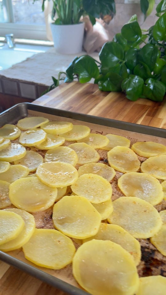 Sliced yellow potatoes arranged on a baking sheet.