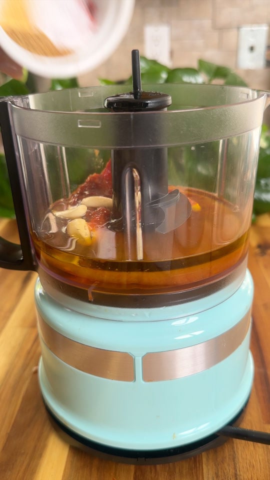 Food processor with oil, garlic, and other ingredients.
