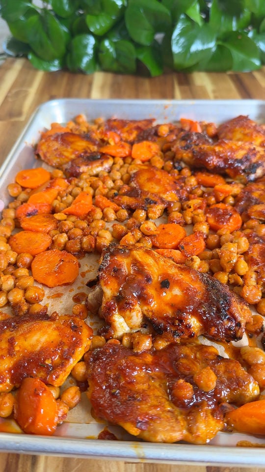 Roasted chicken thighs with chickpeas and carrots on a baking sheet.