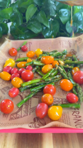 Colorful cherry tomatoes and asparagus on a baking sheet.