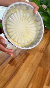 Hands holding a fluted baking pan dusted with semolina.