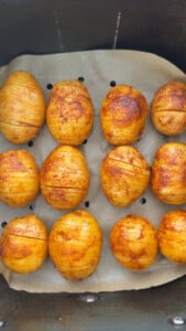 Seasoned potatoes with cuts, arranged in air fryer.
