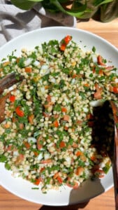 A bowl of tabbouleh salad with couscous, tomatoes, onions, and parsley.