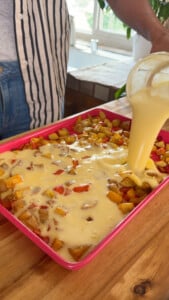 Pouring egg mixture over diced potatoes and vegetables.