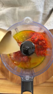 Pouring sauce ingredients into a food processor.