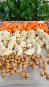 Chopped sweet potatoes, cauliflower, and chickpeas on a baking tray.