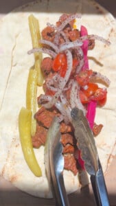 Grilled meat wrap with onions, tomatoes, pickles on a pita bread.