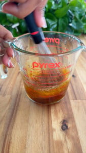 Whisk mixing sauce ingredients in a Pyrex measuring cup.