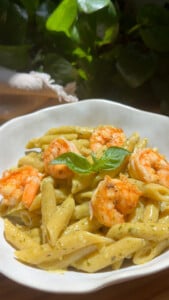Pasta dish with shrimp in creamy sauce, garnished with fresh basil leaves.