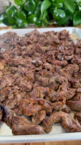 Cooked beef pieces on a metal tray.