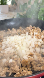 Cooking ground meat with chopped onions in a skillet.