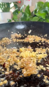 Sautéing onions and garlic in a black skillet.