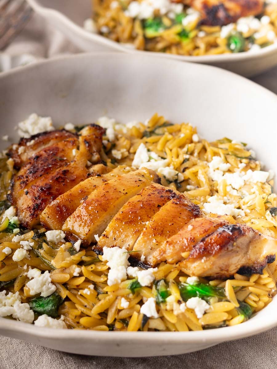 Chicken spinach orzo with spinach and crumbled feta in a white bowl.