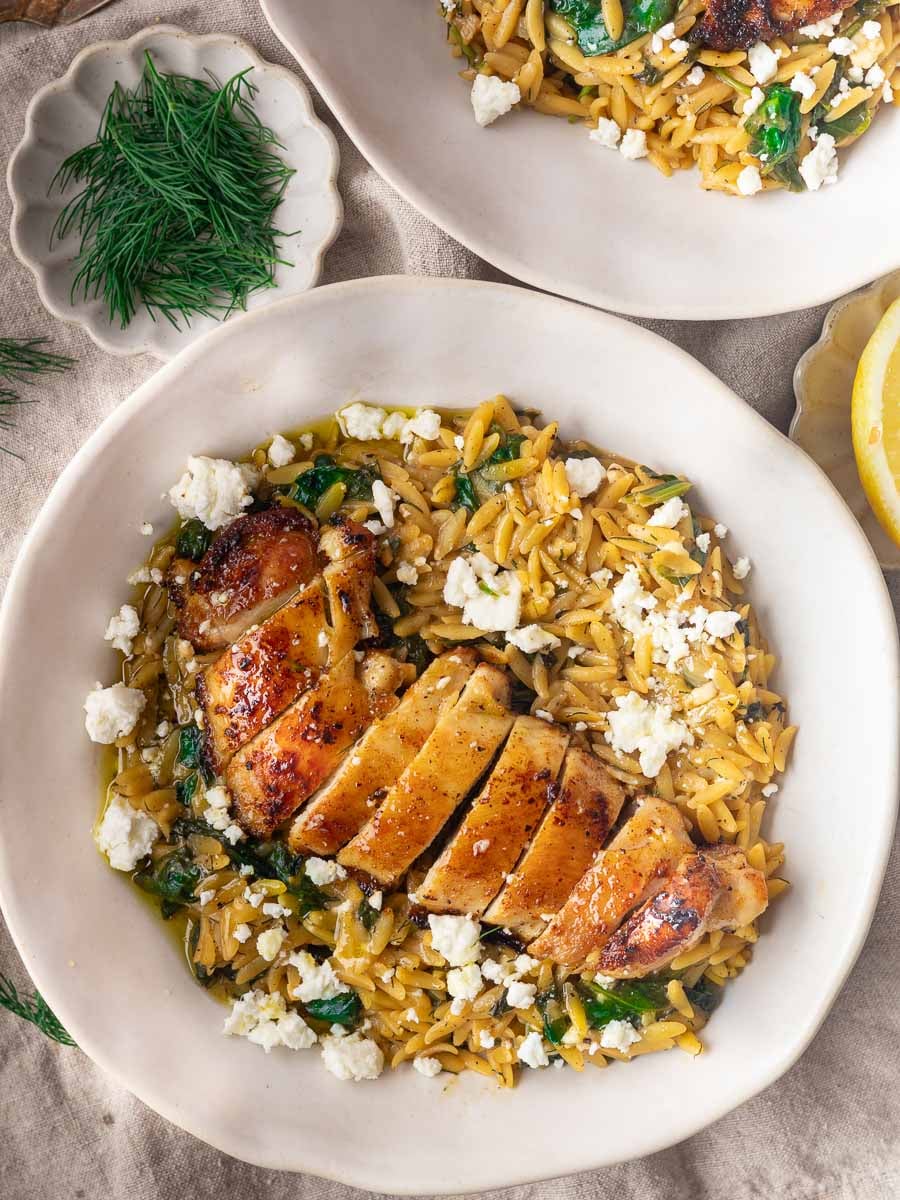 Chicken spinach orzo with spinach and feta, garnished with fresh dill on a white plate.