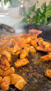 Cooking seasoned chicken pieces in a hot skillet.