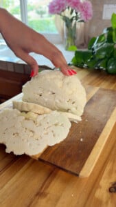 Sliced cauliflower on wooden cutting board.