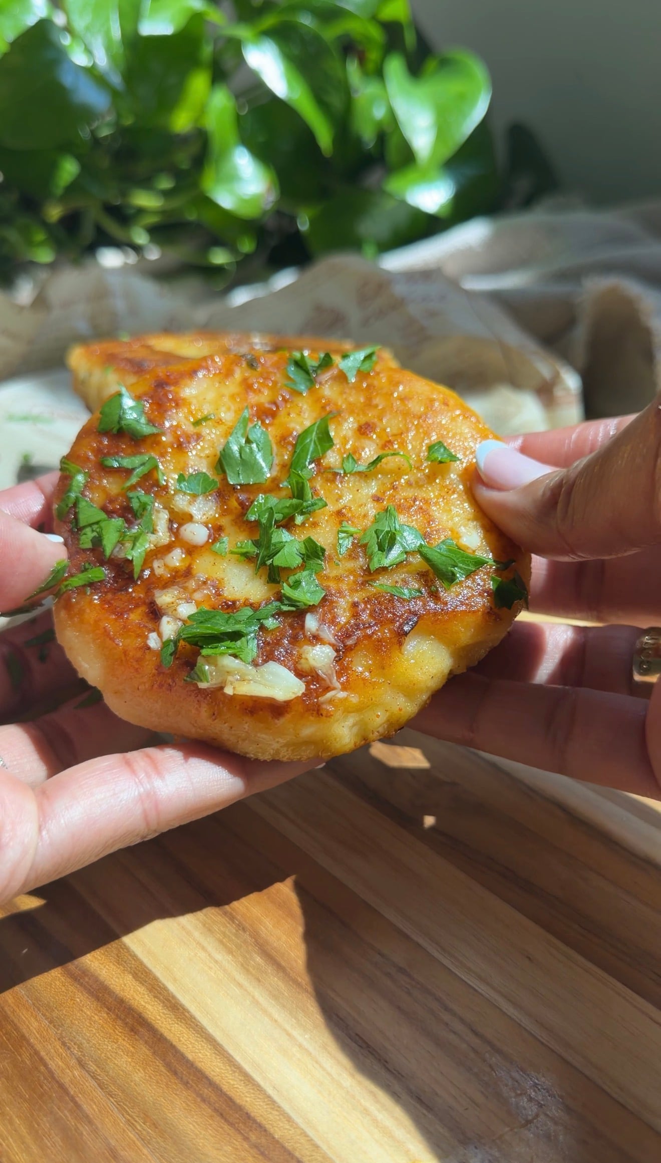 Person holding a freshly cooked stuffed tuna potato cake garnished with parsley.