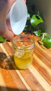 Pouring olive oil into a glass jar on a wooden board.