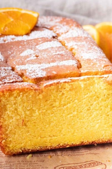 Close-up of a freshly baked orange blender cake topped with powdered sugar and orange slices.