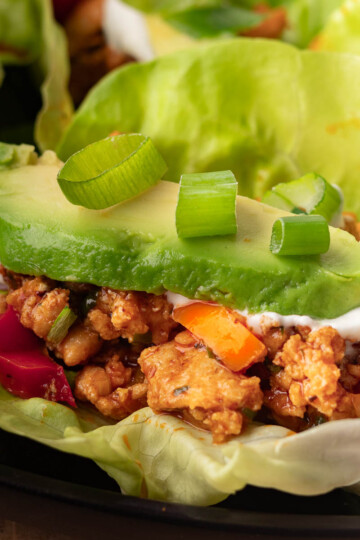 Chicken and pepper lettuce cups with seasoned chicken, sliced avocado, and green onions.