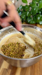 Mixing batter with chopped nuts in a stainless steel bowl.