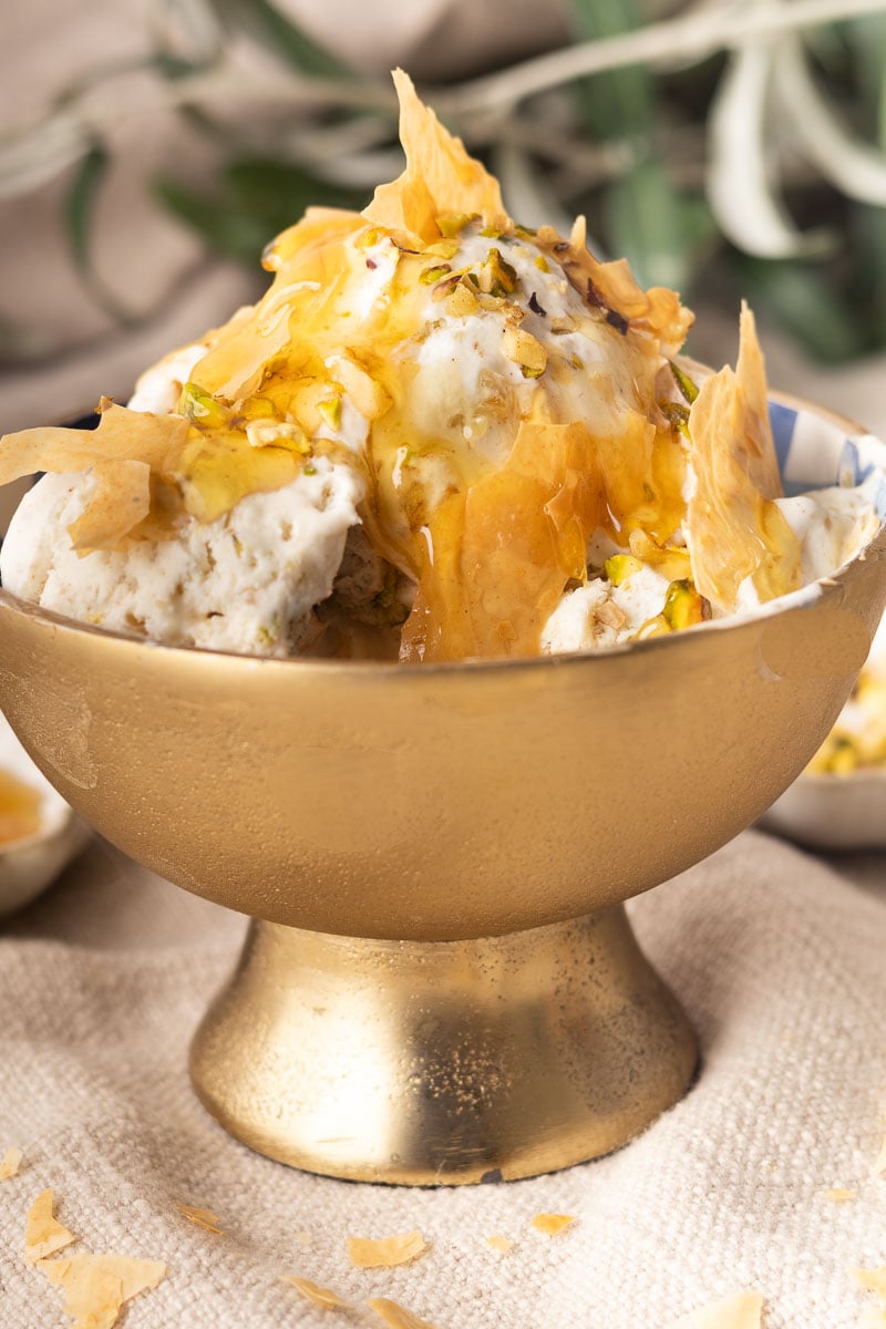 Creamy no-churn baklava ice cream, topped with honey, pistachios, and crispy filo pastry in a gold bowl.