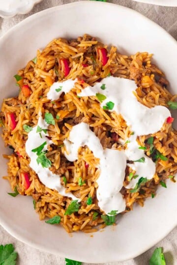 Stuffed pepper bowl topped with yogurt sauce in a white bowl.