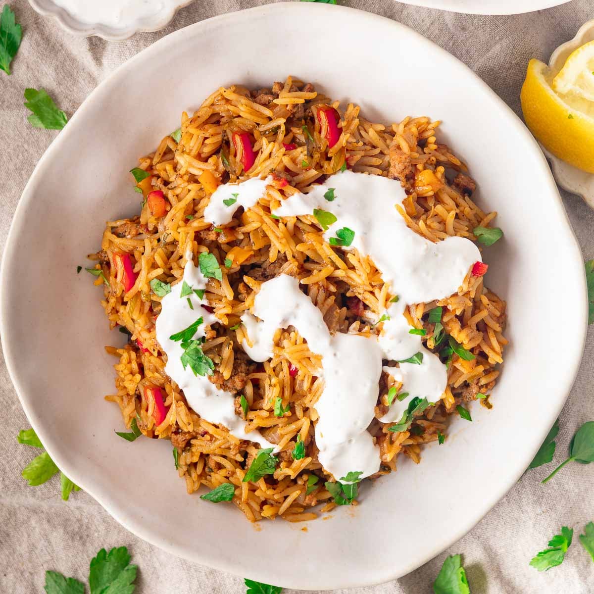 Stuffed pepper bowl topped with yogurt sauce in a white bowl.