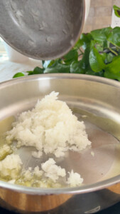 Chopped onions being added to a skillet with oil for cooking.