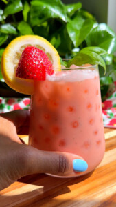 Refreshing strawberry lemon smoothie with fresh basil garnish in a glass.