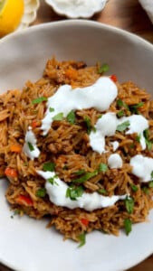 Stuffed pepper bowl topped with yogurt and herbs in a white bowl.