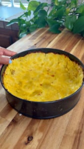 Baked potato crust in springform pan on wooden countertop.