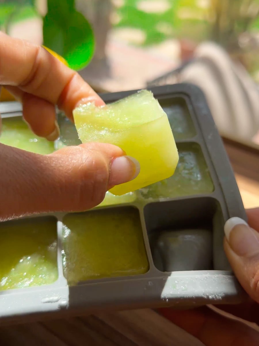 Person holding a green ice cube tray, removing a single electrolyte ice cube.