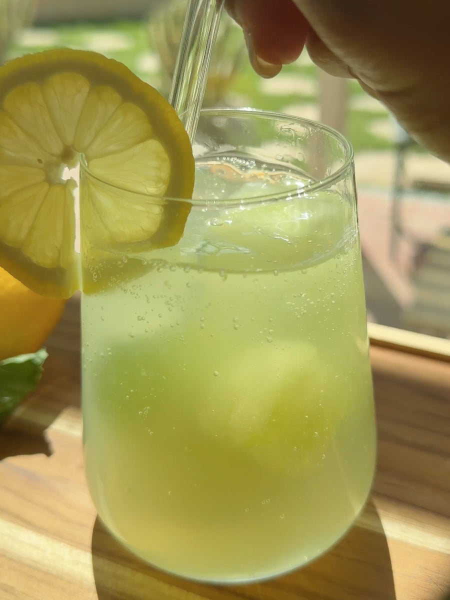 Refreshing drink in a glass with a lemon slice and straw.