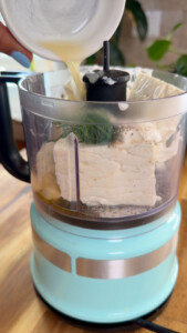 Mixing ingredients for whipped feta in a turquoise food processor.