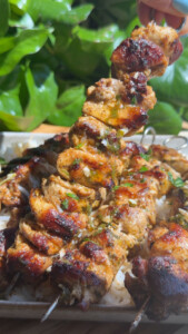Grilled chicken skewers with herbs on a bed of rice, garnished with fresh parsley.