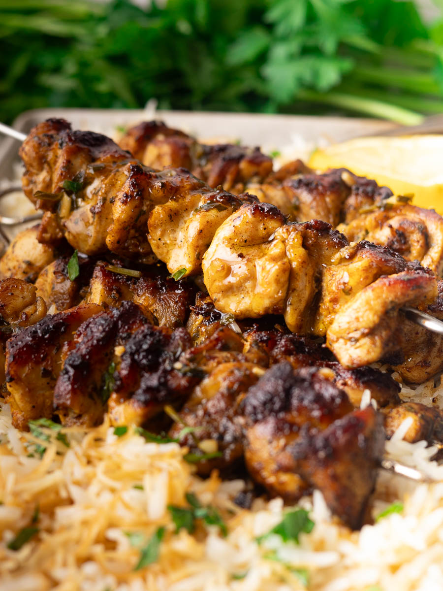 Grilled chicken pinchos morunos on skewers with rice and herbs.